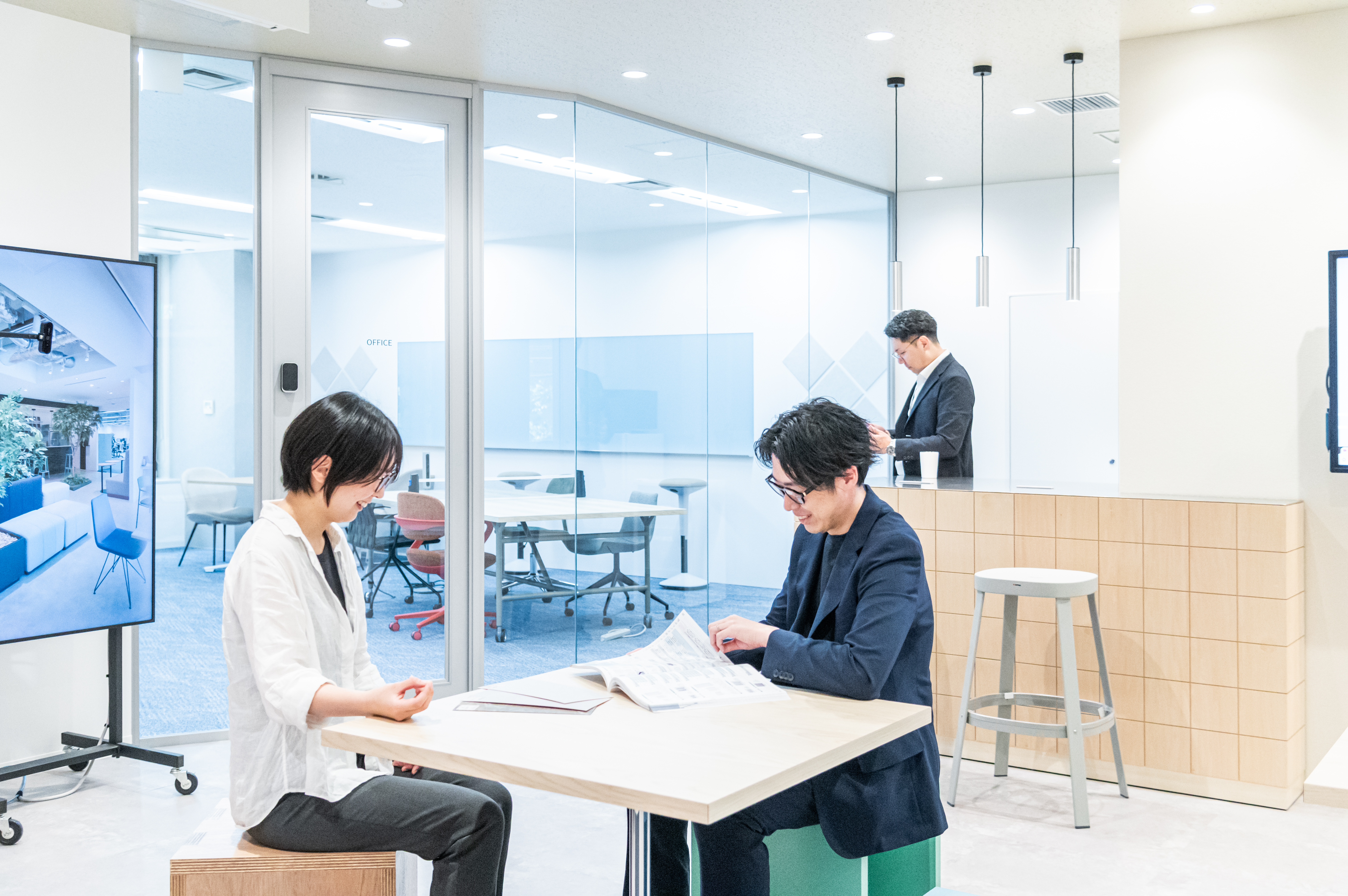 オフィスの共有スペースで打ち合わせをする社員